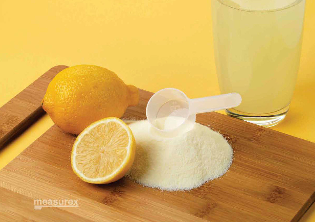 A plastic measuring scoop on top of sugar, used to measure, for lemonade juice.